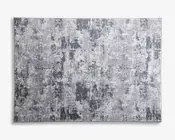 Rektangulært tæppe med et moderne abstrakt mønster i forskellige nuancer af grå og hvid. Designet har et slidt, tekstureret udseende med uregelmæssige felter og penselstrøg-lignende detaljer, hvilket giver det et moderne og alsidigt udtryk. Overfladen ser blød og flad ud, velegnet til mange forskellige indretningsstile.