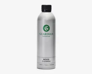 En høj, cylindrisk sølvfarvet flaske med sort skruelåg. Etiket med et grønt 'G'-logo og teksten 'Guardian Furniture Care' i grønt, samt 'Wood Cleaner' med tydelige sorte bogstaver nedenunder. Flasken har et minimalistisk design med letlæselig tekst og et professionelt udtryk.