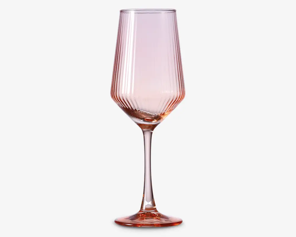Høj, elegant glas med en diskret lyserød tone. Glassets skål har lodrette rillede linjer, der giver en tekstureret overflade, og stilken er slank med samme lyserøde nuance. Bunden er bred og stabil, også med lyserødt skær, hvilket giver glasset et moderne og stilfuldt udtryk.