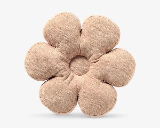Beige, blomstformet pude med seks polstrede kronblade og en rund åbning i midten.