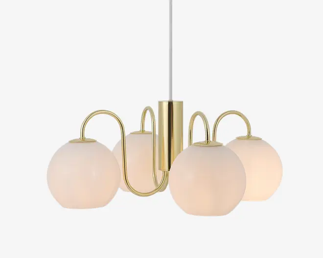 En moderne lysekrone med fire matte glasglobus-skærme, der er symmetrisk placeret omkring en central stang i guldfarvet metal. Hver globus holdes af en buet guldfarvet arm, hvilket giver et elegant og nutidigt udtryk. Lampen hænger i en hvid ledning, og det samlede design kombinerer et stilrent metaludtryk med blødt, diffust lys fra glasskærmene.