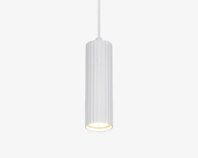 Pendellampe med cylindrisk form og lodrette riller på overfladen. Lampen har en mat hvid finish og et rent, moderne udtryk. Lyset rettes nedad og giver en fokuseret lysstråle, mens den indvendige kant er let tilbagetrukket for at mindske blænding. Ophængt i en matchende hvid ledning.