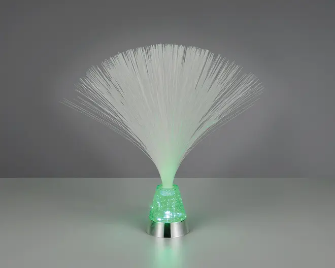 En dekorativ lampe med en samling fine, hvide fiberoptiske tråde, der spreder sig ud fra en lille, konisk fod. Foden er oplyst med et blødt grønt lys, som bevæger sig op gennem fibrene og skaber en glødende effekt. Foden har et tekstureret, krystallignende udseende og en metallisk sølvkant nederst, hvilket giver et moderne præg til designet.