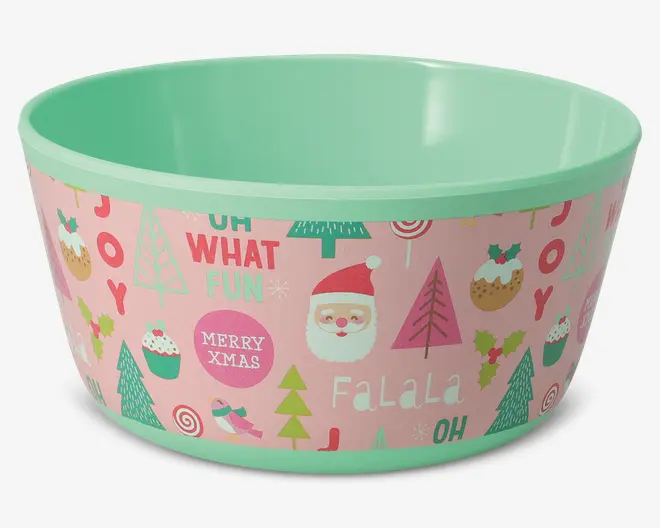 Rund skål med mintgrøn inderside og kant, og en yderside med festligt design på lyserød baggrund. Skålens yderside er dekoreret med julemotiver som julemand, juletræer, cupcakes, småkager, fugle og slik, samt ord som 'JOY', 'OH WHAT FUN', 'MERRY XMAS' og 'FALALA' i forskellige farver og skrifttyper.