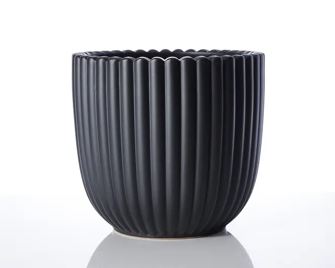 En mat sort beholder med lodrette riller og bølget kant. Formen er cylindrisk med en let afrundet bund, og overfladen har et moderne, minimalistisk udtryk.