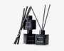 Sæt med tre elegante, sorte, firkantede glasflasker med matchende sorte låg, hver mærket med 'FRAGRANCE' og 'Pepper Balthazar Home Reed Diffuser.' Hver flaske indeholder flere lange, tynde sorte duftpinde til at sprede duften. Designet er moderne og minimalistisk med en blank finish, der giver et luksuriøst udtryk.