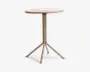 Rundt bord med en glat, lysefarvet bordplade og et centralt metalstel. Stellet deler sig i fire skråtstillede ben for stabilitet, alle med samme lyse finish. Designet er minimalistisk og moderne, velegnet til små rum eller som et accentmøbel.