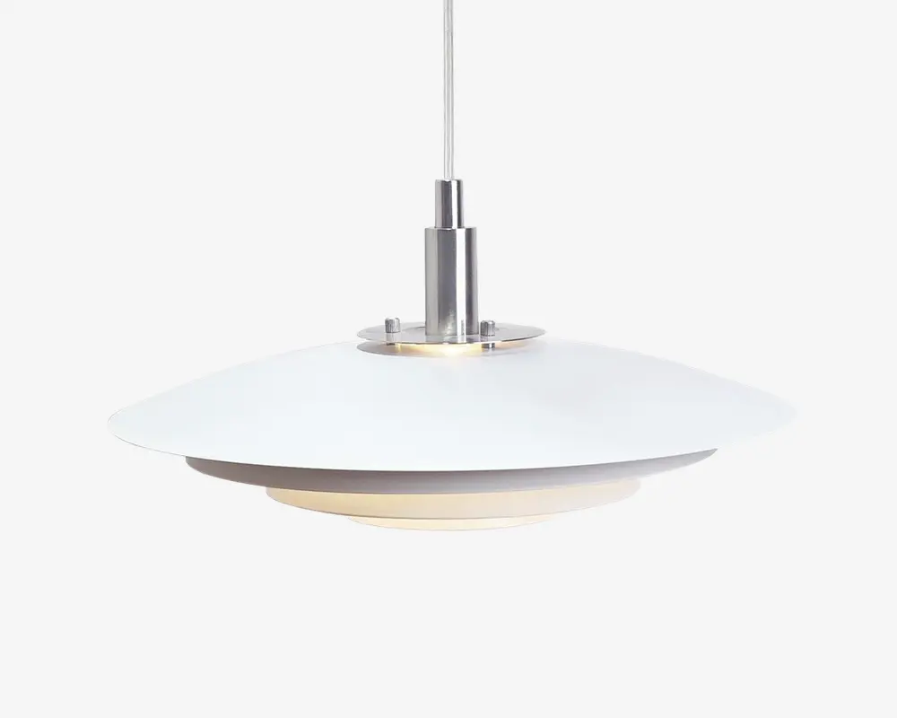 Loftlampe med et moderne, minimalistisk design, der har en bred, flad, hvid metalskærm og en ophængning i børstet metal. Lampen hænger fra en central stang og har en diffus bund, som blødgør lyset og giver en varm, behagelig belysning. De rene linjer og neutrale farver gør lampen velegnet til moderne indretning.