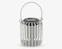 En cylindrisk lanterne med lodrette metalslats i mat hvid finish, udstyret med et rundt håndtag på siderne til nem transport eller ophængning. Lanternens top har en flad, sort overflade med et solpanel, hvilket indikerer, at den er solcelledrevet. Designet gør det muligt for lyset at skinne gennem åbningerne mellem slatsene og skabe en dekorativ effekt.