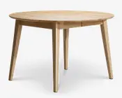 Rundt bord i træ med en glat, lys naturfinish. Bordet har fire let tilspidsede ben, der vinkler udad for stabilitet. Bordpladen har en diskret skrå kant, og det samlede design er minimalistisk og moderne, velegnet til spisning eller mindre sammenkomster.