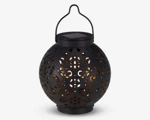 Rund sort lanterne med indviklede udskæringer i overfladen, som lader et varmt gult lys skinne igennem. Lanternen har et håndtag øverst til ophængning og et solcellepanel integreret i låget til opladning. Designet skaber dekorative lysmønstre, når den er tændt.