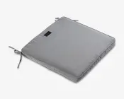 Kvadratisk, lysegrå pude med diskret tekstureret stof. Puden har to stofsnore i to hjørner, så den kan fastgøres til en stol. Den har en kant med piping for ekstra holdbarhed og et lille sort mærke syet på den ene side. Puden er moderat tyk og giver behagelig polstring.