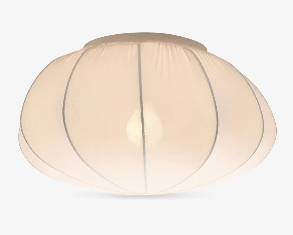 En kuppelformet lampeskærm lavet af gennemsigtigt hvidt stof med lodrette syninger, der giver et blødt segmenteret udtryk. Materialet spreder lyset jævnt og skaber en varm og hyggelig belysning. Designet er minimalistisk og moderne, velegnet til forskellige indretninger.