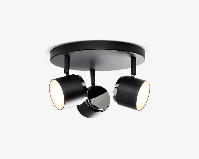 Moderne loftlampe med mat sort finish, der har tre justerbare cylindriske spots monteret på en rund base. Hver spot kan rettes individuelt, hvilket giver mulighed for fleksibel belysning. Lampen har et stilrent, minimalistisk design med glatte overflader og diskrete kromdetaljer ved samlingerne.