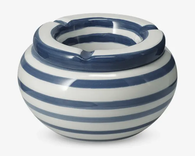 Rundt keramisk produkt med bred åbning og tre riller i kanten, dekoreret med håndmalede blå og hvide vandrette striber. Overfladen er blank, og striberne er let ujævne, hvilket giver et håndlavet udtryk.