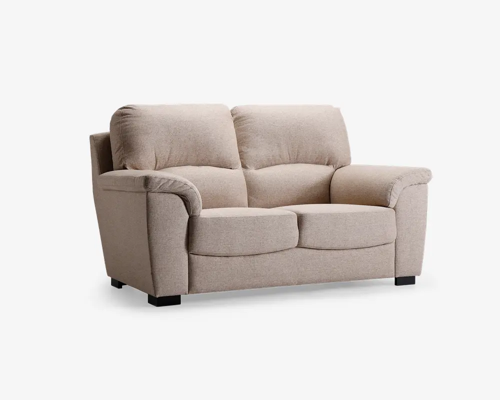 En to-personers sofa betrukket med lysebeige stof, med bløde, fyldige ryghynder og brede, polstrede armlæn. Sædehynderne er tykke og let afrundede for ekstra komfort. Sofaen står på korte, solide sorte ben, hvilket giver et moderne og hyggeligt udtryk.