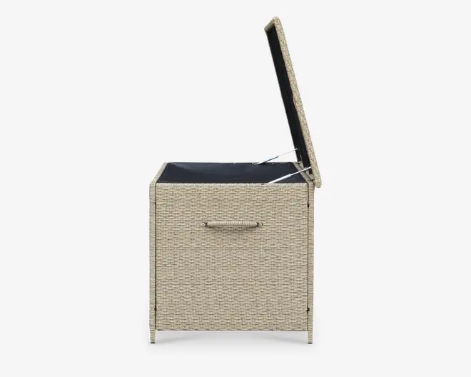 Rektangulær opbevaringskasse med flettet rattan-lignende ydre i en lys beige farve. Låget er åbent og afslører et rummeligt sort indre. Kassen har et solidt håndtag på forsiden for nem transport og står på fire korte ben for stabilitet.