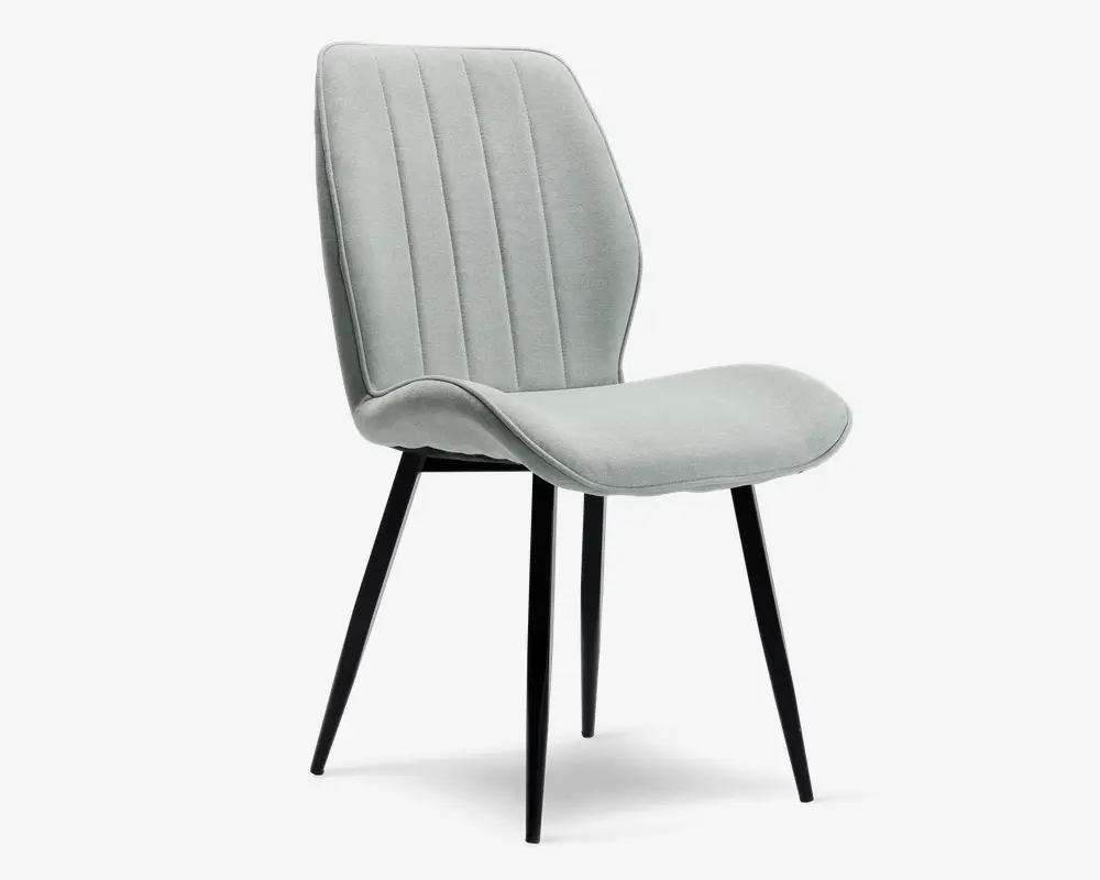 Stol med lysegråt polstret sæde og ryglæn, der har lodrette syninger for ekstra struktur. Sædet og ryglænet er let buede og ergonomisk formet for komfort. Stolen står på fire slanke, sorte metalben, der er let skråtstillede og giver et moderne og minimalistisk udtryk.