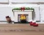 En miniature dekorativ pejs med hvid murstensdesign, der har en realistisk ild med gule og orange flammer. Karmen er pyntet med grøn guirlande og en rød sløjfe, hvilket giver et festligt udtryk. Til venstre står en lille kurv med brændestykker. Foran pejsen står et par små røde støvler med hvid pelskant, hvilket antyder et juletema. Detaljerne er fint udført, hvilket gør den velegnet til dukkehuse eller juleudstillinger.