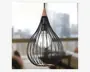 Loftlampe med et dråbeformet åbent burdesign lavet af tynde sorte metalstænger, med en synlig vintage-inspireret glødepære i midten. Top- og bunddetaljer er udført i en varm træfarve, hvilket giver et elegant og kontrastfuldt udtryk.