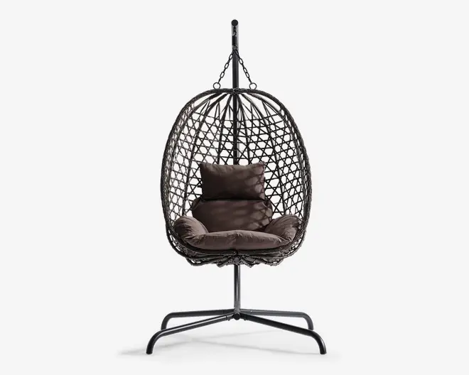 Hængende æggeformet stol med en flettet ramme i rattan-stil, understøttet af et robust metalstativ. Stolen har bløde, mørkebrune hynder til sidde- og rygstøtte samt en ekstra pude for øget komfort. Den åbne gitterstruktur giver god luftcirkulation og et moderne udseende.