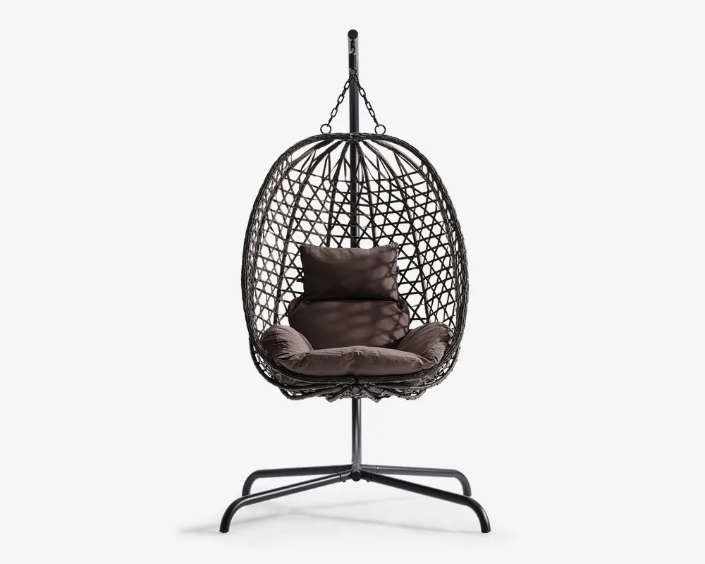 Hængende æggeformet stol med en flettet ramme i rattan-stil, understøttet af et robust metalstativ. Stolen har bløde, mørkebrune hynder til sidde- og rygstøtte samt en ekstra pude for øget komfort. Den åbne gitterstruktur giver god luftcirkulation og et moderne udseende.