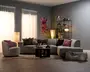 Moderne grå modulsofa med chaiselong, matchende lænestol og lavt rundt sofabord, stylet med rosa og mørke pyntepuder, et lille tæppe, gulvlamper, reol og farverig vægkunst.