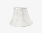 En klokkeformet lampeskærm lavet af hvidt stof med et diskret tekstureret mønster. Skærmen har en let udvidet bund og en smallere top, med lodrette syninger, der giver struktur. Stoffet har en let glans, hvilket giver et elegant udtryk.
