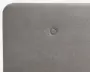 Nærbillede af en rektangulær, polstret overflade i lysegråt stof med en enkelt centralt placeret knap. Kanterne er blødt afrundede, og stoffet har en diskret vævet struktur.