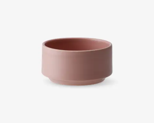 En rund skål med mat finish i en afdæmpet rosa farve. Skålen har lige sider og en flad bund med en let kant, hvilket giver den et moderne og minimalistisk udtryk. Overfladen er glat og uden dekoration, hvilket fremhæver det enkle design.
