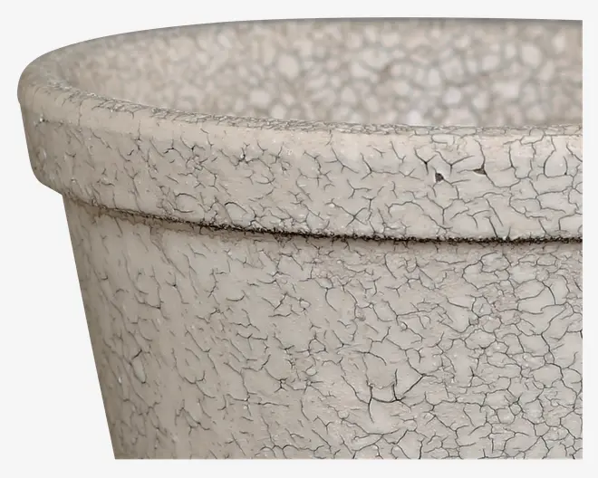 Nærbillede af en rund beholder med bred kant, der har en tekstureret, krakeleret overflade i en lys beige farve. Overfladen giver et gammelt, patineret udseende, og materialet ligner keramik eller ler.