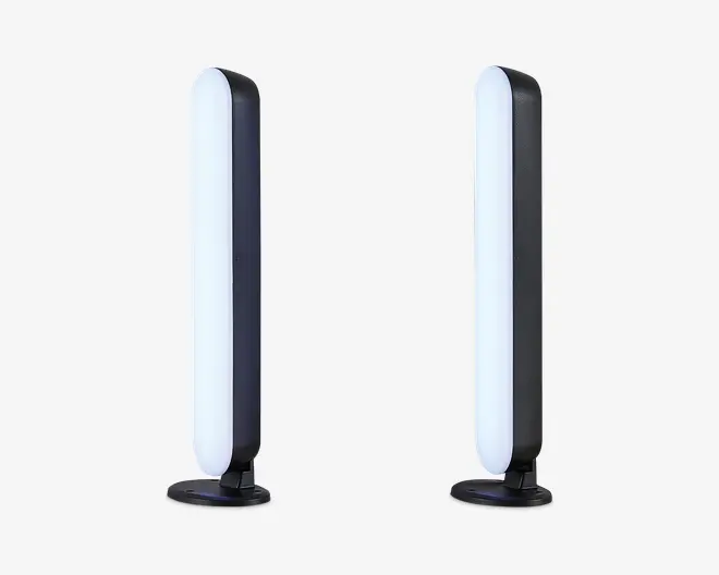Et par slanke, lodrette LED-lysstænger med afrundede kanter, monteret på cirkulære sorte baser. Lysene har et moderne, minimalistisk design med en hvid oplyst front og en mat sort bagside. Velegnet til placering på skrivebord eller hylde og giver stemnings- eller accentbelysning.