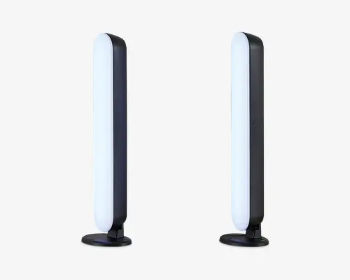 Et par slanke, lodrette LED-lysstænger med afrundede kanter, monteret på cirkulære sorte baser. Lysene har et moderne, minimalistisk design med en hvid oplyst front og en mat sort bagside. Velegnet til placering på skrivebord eller hylde og giver stemnings- eller accentbelysning.