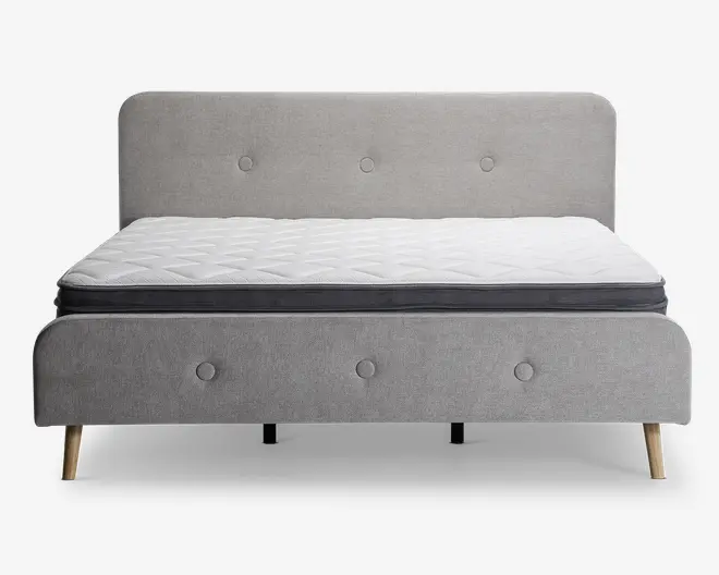 En moderne sengeramme med et lysegråt polstret hovedgærde og fodgærde, begge med knapdetaljer. Sengen står på fire skrå træben, hvilket giver et moderne udtryk. Madrassen er hvid med quiltet mønster og har en mørkegrå kant, hvilket giver et rent og stilfuldt udseende.