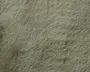 Nærbillede af et blødt materiale med kort luv og en diskret, naturlig tekstur. Overfladen fremstår glat med fine, tætte fibre i en afdæmpet grågrøn farve, hvilket giver et plysset og hyggeligt udtryk. Teksturen er ensartet med lette variationer i nuancer og fibrenes retning.