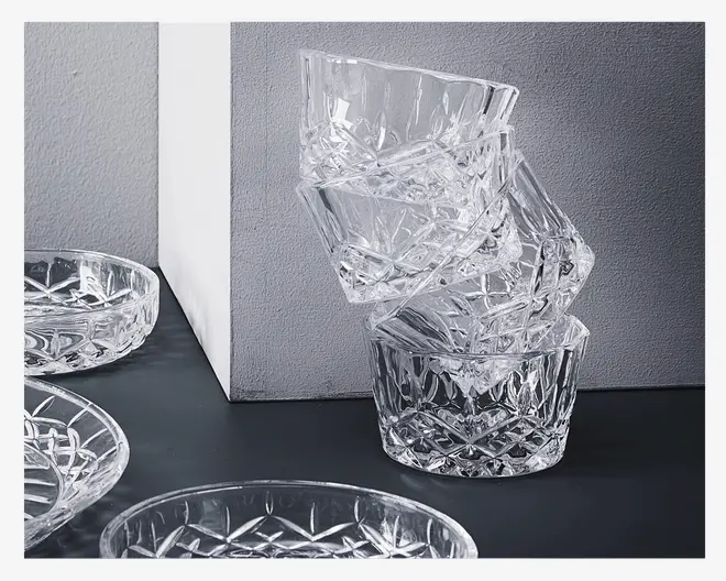 Stablede klare glasskåle med et facetslebet, diamantmønstret design på siderne og bunden, hvilket giver dem et glitrende og elegant udseende. Skålene er runde med tykke, robuste kanter. Designet reflekterer lyset og skaber en dekorativ effekt, der egner sig godt til servering af desserter eller snacks.