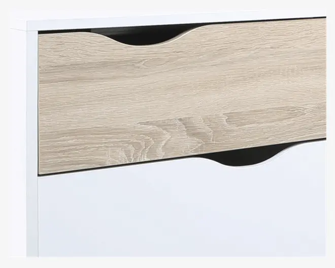 Nærbillede af et møbel med en skuffe i lyst trælook og hvid ramme. Skuffen har et buet udskåret greb øverst, og sektionen nedenunder er helt hvid med en tilsvarende buet udskæring for nem åbning. Designet er moderne og minimalistisk med glatte overflader og rene linjer.