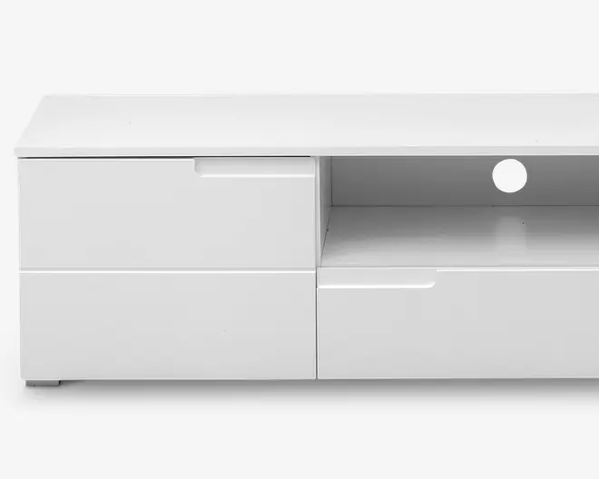 Rektangulært, moderne hvidt TV-bord med blank overflade. Har to store skuffer til venstre, én bred skuffe til højre og en åben hylde øverst til højre med et rundt hul til kabelgennemføring bagest. Skufferne har integrerede greb for et stilrent, grebsløst udtryk.