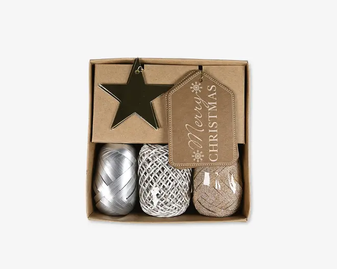 Gaveindpakningssæt med et stjerneformet ornament i metalguld, et brunt gavemærke med teksten 'Merry Christmas' i hvid skrift og snefnugdetaljer, en rulle skinnende sølv gavebånd, en rulle hvidt og sølvfarvet snor samt en rulle guldglitterbånd. Alle dele er pænt arrangeret i en brun papæske med separate rum.