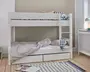 Hvid køjeseng i træ med et minimalistisk design, bestående af to enkeltsenge stablet oven på hinanden. Sengen har en indbygget stige i højre side for nem adgang til overkøjen. Begge køjer har enkle sengeheste for sikkerhed. Under den nederste køje er der to rummelige udtræksskuffer til ekstra opbevaring. Sengetøjet er i neutrale farver med stribede og geometrisk mønstrede puder, og et blåt ternet klæde hænger fra stigen. Sengen står på et lyst trægulv ved siden af et hvidt radiatorcover og en lille skrivebordslampe.