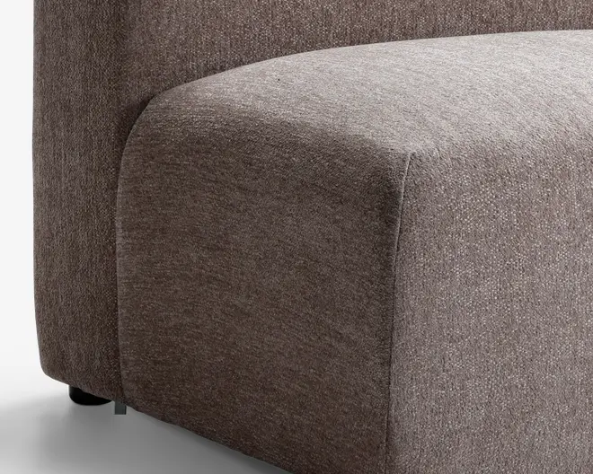 Nærbillede af et sofahjørne med en glat, afrundet armlæn og sæde. Betrækket er et tekstureret, mellembrunt stof med et diskret vævemønster. Designet er moderne og minimalistisk med rene linjer og et blødt, polstret udseende.
