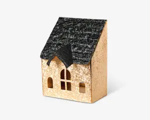 Lille dekorativt hus med en sort, tekstureret tag og en beige facade med let glimmer. Forsiden har tre buede vinduer og et centralt rektangulært vindue med krydsdesign samt en lille gavl over indgangen. Udseendet er rustikt og charmerende, velegnet til jule- eller boligindretning.