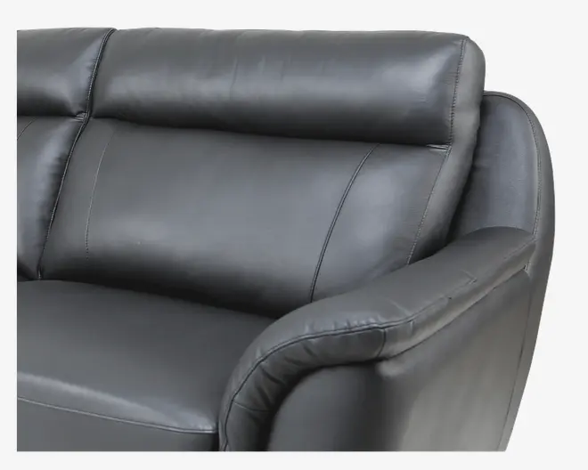 Nærbillede af en sofa med glat, sort læderbetræk. Sæde- og ryghynderne er bløde og velpolstrede med diskrete syninger. Armlænet er bredt og let buet for komfort, og det samlede design har et moderne og stilrent udtryk.