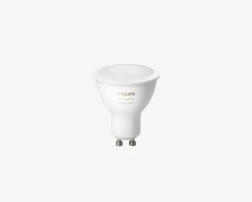 Kompakt LED-spotpære med GU10-fatning og mat hvid finish. Pæren har en bred, flad top for jævn lysfordeling og er mærket med 'PHILIPS Hue white and color.' Den er designet til smart belysning med justerbare farve- og lysstyrkeindstillinger. Fatningen har to korte stifter til sikker montering i kompatible sokler.