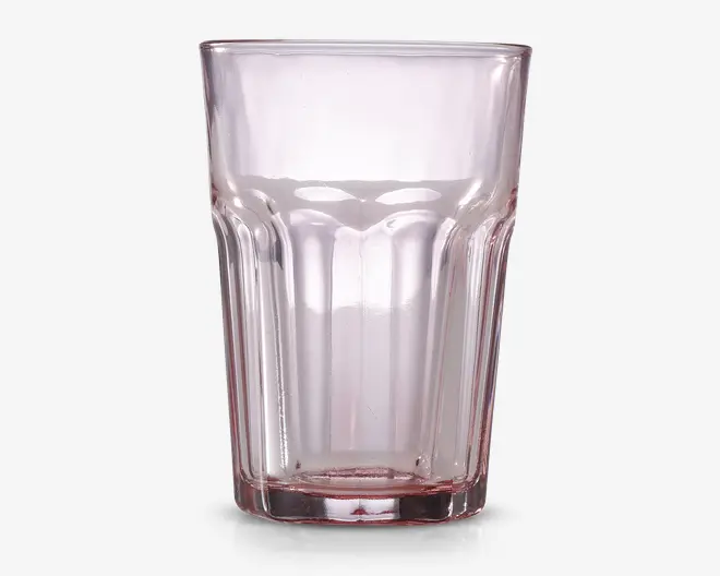 Klar glas tumbler med en let lyserød tone, der har et facetteret design med lodrette riller langs siderne for bedre greb. Glasset har en tyk, robust bund og en bred åbning øverst.