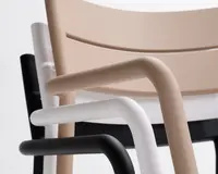 Nærbillede af tre stablede stole, hver med en glat, afrundet ramme og armlæn. Stolene har forskellige farver: beige, hvid og sort. Designet er minimalistisk og moderne med blødt buede ryglæn og armlæn, der passer pænt sammen, når stolene stables.