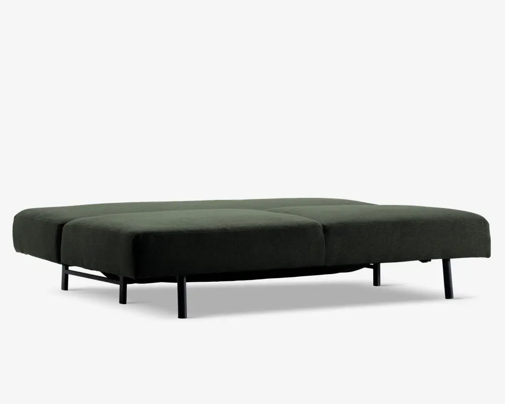 Lavt, rektangulært møbel med mørkegrønt polstret overflade, opdelt i fire bløde sektioner. Støttes af slanke, sorte metalben, hvilket giver et moderne og minimalistisk udtryk. Stoffet ser blødt ud, og designet er enkelt og funktionelt.