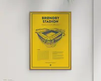 En indrammet plakat med en klar gul baggrund og en tynd sort kant. Plakaten viser en detaljeret, håndtegnet illustration af et stadion i blå blæk, placeret over midten. Titlen 'BRØNDBY STADION' står med store, fede blå bogstaver øverst. Under illustrationen er der et tekstafsnit, der giver historisk information om stadionet, også i blå. Designet er minimalistisk og moderne med en stærk kontrast mellem den gule baggrund og det blå motiv og tekst.