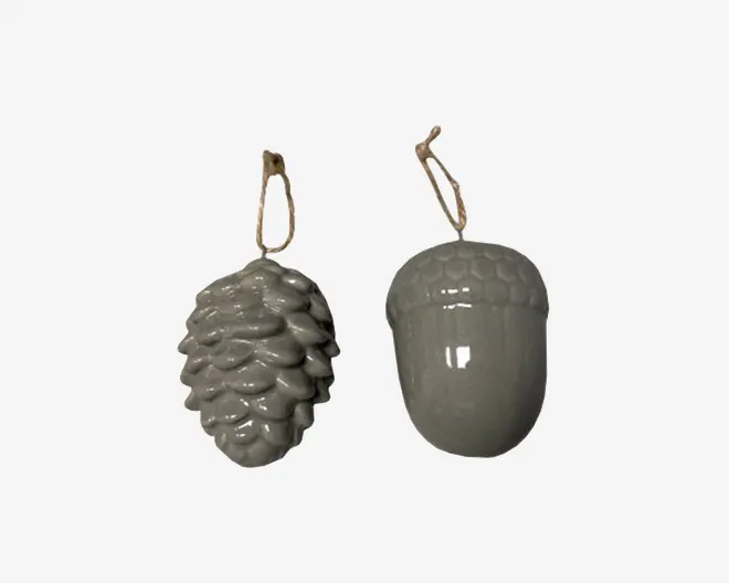 Sæt med to blanke keramikornamenter, den ene formet som en grankogle og den anden som et agern. Begge har en glat, ensartet grå farve og er udstyret med en naturfarvet snor til ophængning. Grankoglen har detaljerede, lagdelte skæl, mens agernet har en rund krop med en struktureret top.