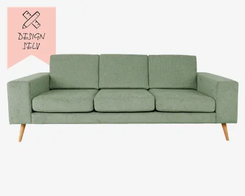En moderne sofa med et minimalistisk design, der har tre sædehynder og tre ryghynder. Betrækket er i en afdæmpet grøn farve med en let tekstur. Sofaen har lige, brede armlæn og står på fire skrå, lyse træben, hvilket giver den et skandinavisk udtryk.